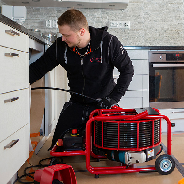 Plumber using a miller system to clean a drain under a residential sink